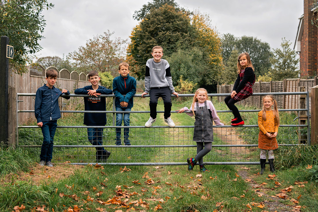 Group of children seven cousins sat on a farm gate