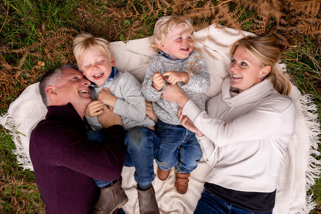family laying down on blanket laughing together 