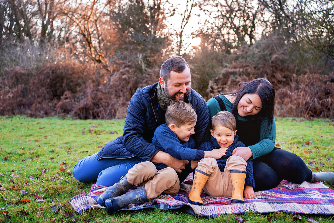 family sat on a blanket at sunset in Savernake forest 