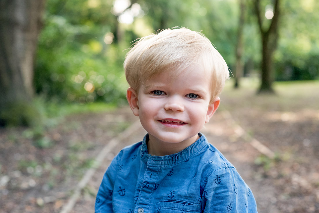 young boy wearing blue shirt sming at camera 