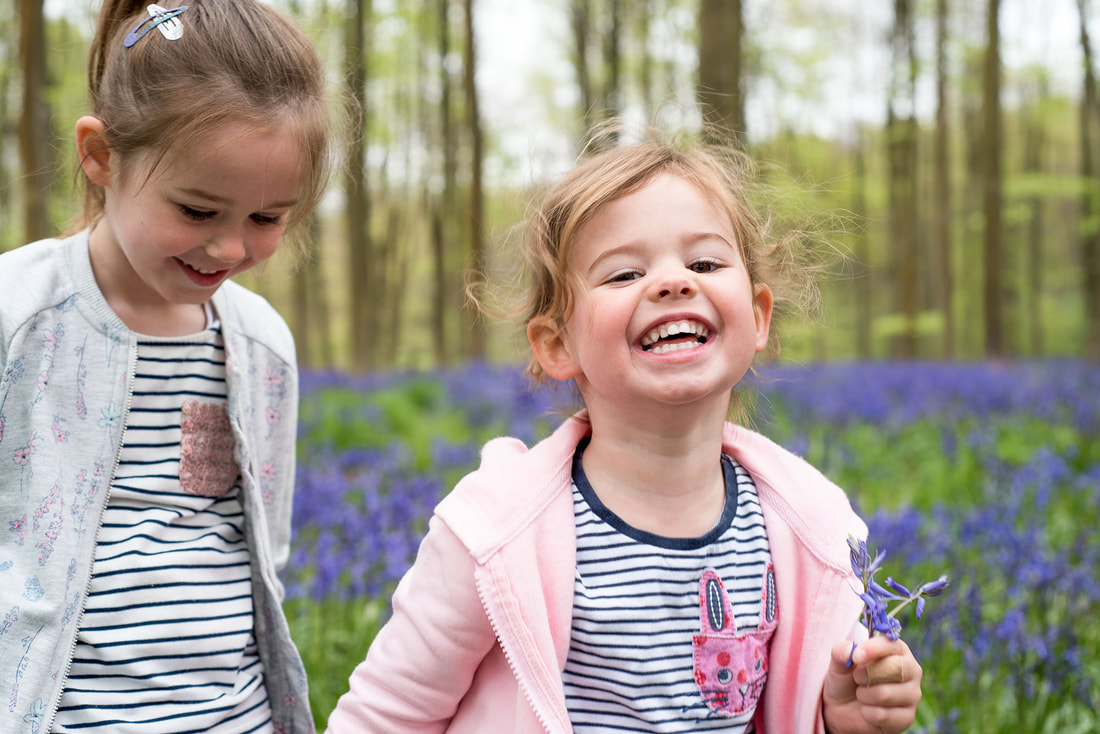 two girls smiling and laughing whilst walking through bluebell woods