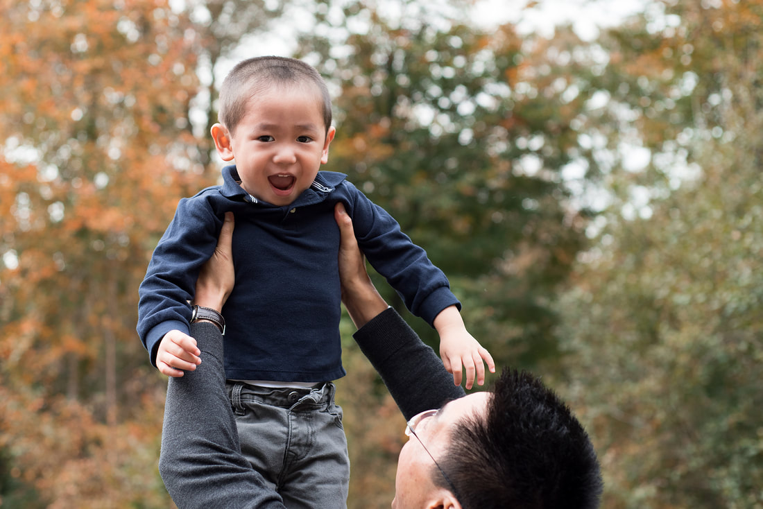 boy laughing whilst being lifted into the air 